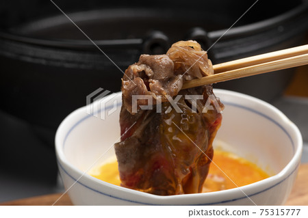 Eat sukiyaki meat with beaten egg 75315777