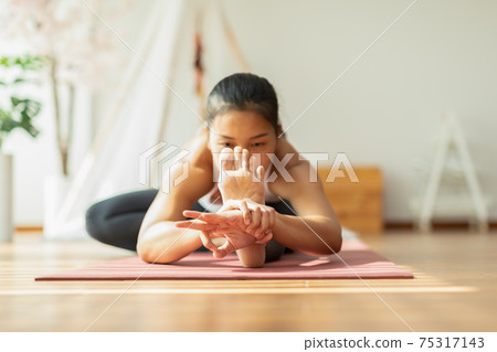 Calm of Athletic Healthy Asian woman in sportswear workout yoga sitting forward fold pose excercise on yoga mat at home in bedroom,healthy lifestyle concept Calm of Athletic Healthy Asian woman in sportswear workout yoga sitting forward fold pose excercise on yoga mat at home in bedroom,healthy lifestyle concept 75317143