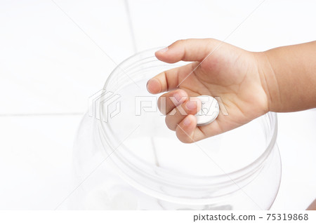 selective focus of kid's hand picked up dollar coin to jar with selective focus of kid's hand picked up dollar coin to jar with 75319868