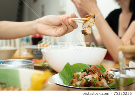 Girl picks up Deep Fried Pork on Chopstick with spicy chili on plate Girl picks up Deep Fried Pork on Chopstick with spicy chili on plate 75320236