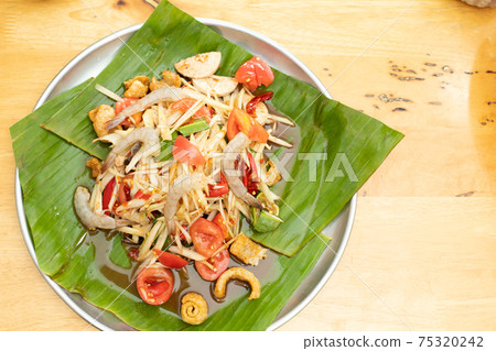 Spicy Papaya Salad and raw prawn spice on banana leaf Spicy Papaya Salad and raw prawn spice on banana leaf 75320242