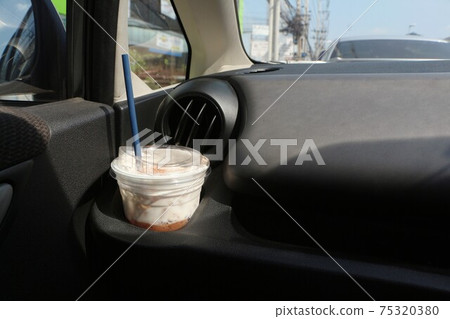 Plastic beverage cups are placed in the cup holder in the car. Cup of iced coffee in car. 75320380