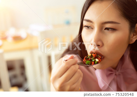 Woman eats Chili spicy and hanging on spoon to mouth Woman eats Chili spicy and hanging on spoon to mouth 75320548