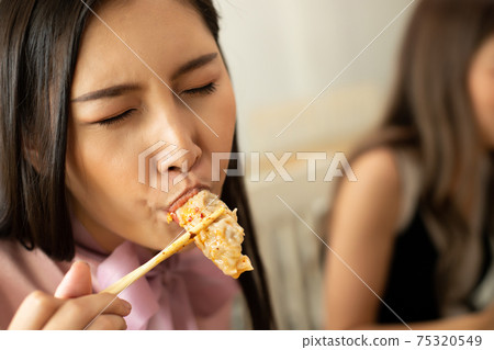 Woman eats Chili spicy Wonton and hanging to mouth Woman eats Chili spicy Wonton and hanging to mouth 75320549