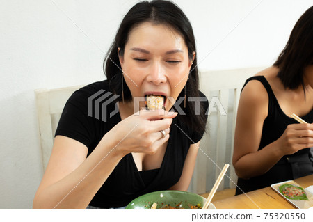 Woman eats Chili spicy Wonton and hanging to mouth Woman eats Chili spicy Wonton and hanging to mouth 75320550