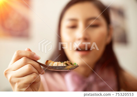 Woman eats Chili Spicy Deep Fried Pork and hanging on spoon Woman eats Chili Spicy Deep Fried Pork and hanging on spoon 75320553