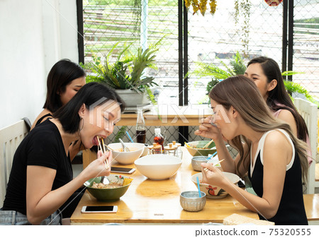Woman eats spicy hot tomyum noodle soup and hanging on chopstick Woman eats spicy hot tomyum noodle soup and hanging on chopstick 75320555