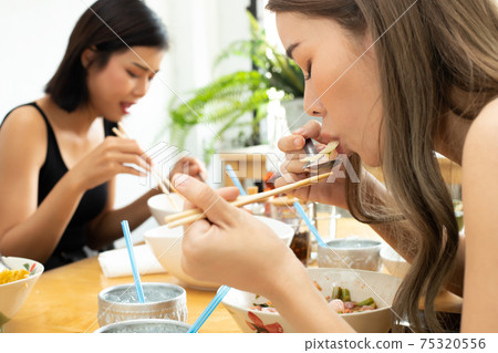 Woman eats spicy hot tomyum noodle soup and hanging on chopstick Woman eats spicy hot tomyum noodle soup and hanging on chopstick 75320556