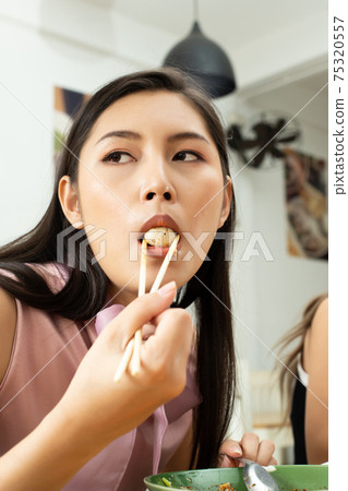 Woman eats spicy hot tomyum pork ball and hanging on chopstick Woman eats spicy hot tomyum pork ball and hanging on chopstick 75320557