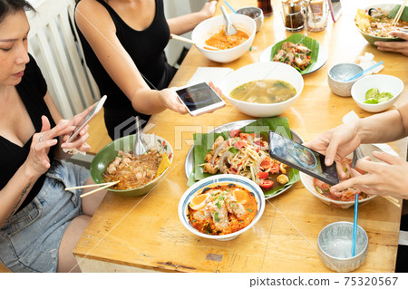 Girl takes photo with smart phone of Delicious and good looking Food 75320567