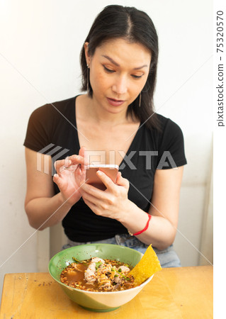 Girl takes photo with smart phone of Delicious and good looking Food Girl takes photo with smart phone of Delicious and good looking Food 75320570