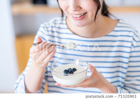 Young woman eating yogurt Young woman eating yogurt 75320901