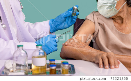 Doctor doing vaccine injection to senior woman. 75321866