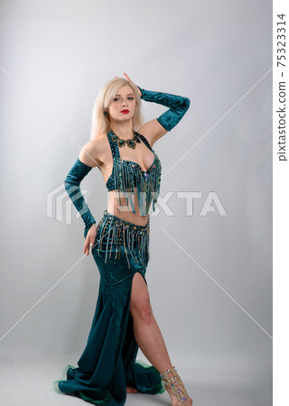 Young beautiful exotic eastern women performs belly dance in ethnic green dress. Young beautiful exotic eastern women performs belly dance in ethnic green dress. 75323314