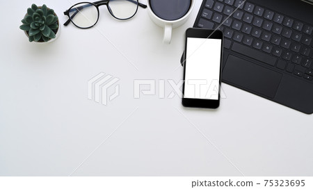 Top view of smart phone with empty screen, coffee cup, plant, glasses and copy space on white office desk. 75323695
