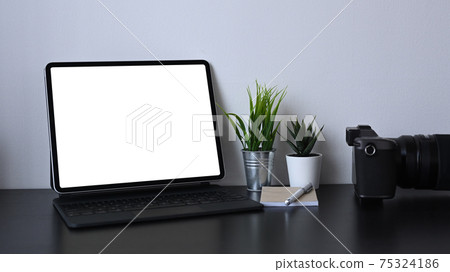 Mock up computer tablet with blank screen, house plant and camera on black table. Mock up computer tablet with blank screen, house plant and camera on black table. 75324186