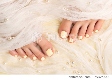 Beautiful womans legs with summer nail design on yellow fabric 75325848
