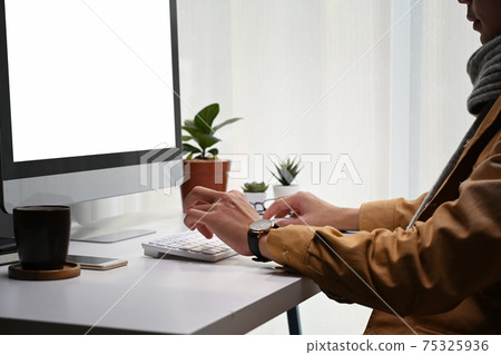 Cropped shot of young man looking at computer screen and working on project in modern office. Cropped shot of young man looking at computer screen and working on project in modern office. 75325936