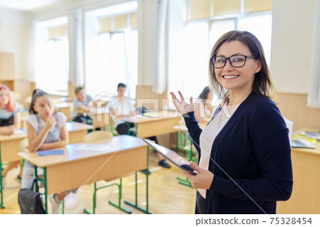 Portrait of female teacher with digital tablet at school at lesson 75328454
