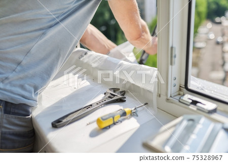 Installing an air conditioner in an apartment office, close-up of an technician hands 75328967