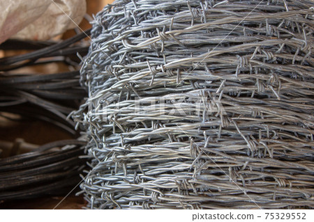 Rolls of barbed wire used for building cattle fences Rolls of barbed wire used for building cattle fences 75329552