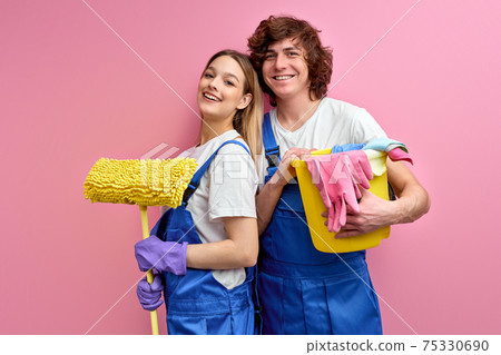 cheerful couple use rags and other tools for cleaning, posing at camera 75330690