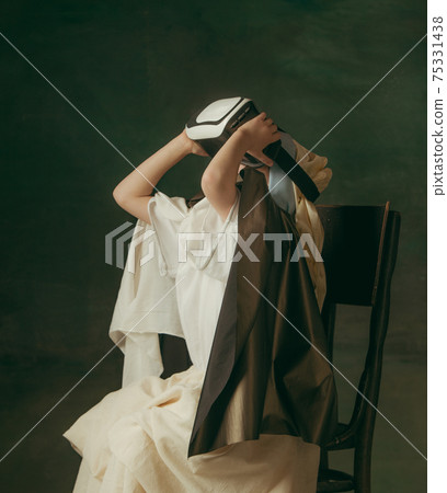 Medieval little girl as a lady with a pearl earring on dark studio background. Concept of comparison of eras, childhood. Stylish creative design, art vision, new look of artwork. Medieval little girl as a lady with a pearl earring on dark studio background. Concept of comparison of eras, childhood. Stylish creative design, art vision, new look of artwork. 75331438