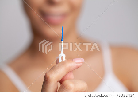 The woman uses brushes to clean the interdental spaces 75332434