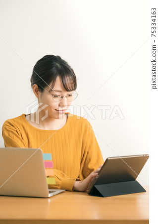 A young woman operating a tablet 75334163