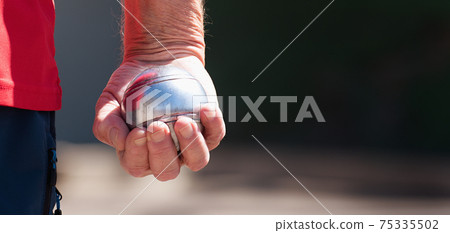 Senior playing petanque fun and relaxing game, man plays petanque with a metal ball in a park Senior playing petanque fun and relaxing game, man plays petanque with a metal ball in a park 75335502