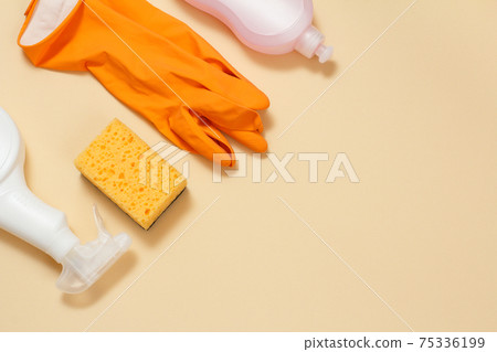 Rubber gloves, bottles of dishwashing liquid and a sponge on a beige background. Rubber gloves, bottles of dishwashing liquid and a sponge on a beige background. 75336199