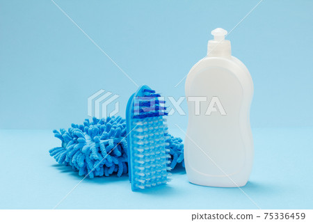 Bottle of dishwashing liquid, a rag and a brushes on a blue background. Bottle of dishwashing liquid, a rag and a brushes on a blue background. 75336459