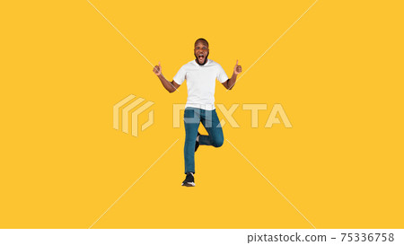 Emotional Black Guy Jumping Gesturing Thumbs Up Over Yellow Background Emotional Black Guy Jumping Gesturing Thumbs Up Over Yellow Background 75336758