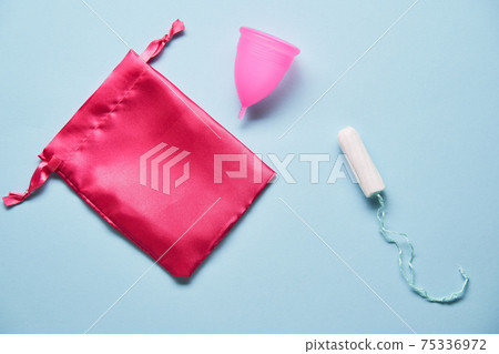Pink menstrual cup and variuos of tampons on blue background Pink menstrual cup and variuos of tampons on blue background 75336972