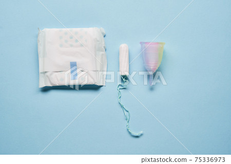 Pink menstrual cup and variuos of tampons on blue background Pink menstrual cup and variuos of tampons on blue background 75336973