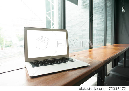 Laptop with blank screen on wooden table in front of office window - technology concept Laptop with blank screen on wooden table in front of office window - technology concept 75337472