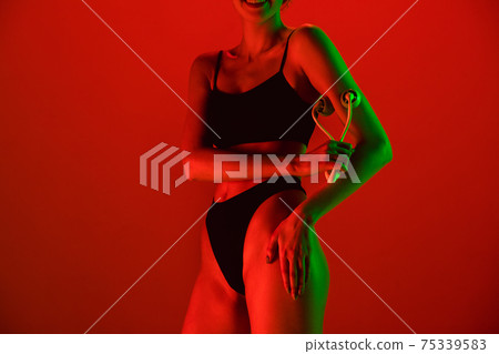 Beautiful female model on orange background in neon light. Beauty, cosmetics, spa, depilation, diet and treatment, fitness concept. 75339583