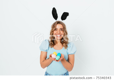 Beautiful happy young woman celebrating Easter wearing bunny ears Beautiful happy young woman celebrating Easter wearing bunny ears 75340343