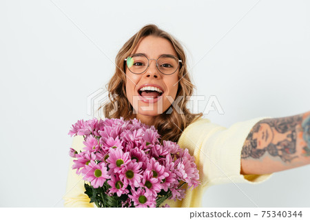 Beautiful smiling young woman wearing glasses holds bouquet of fresh flowers Beautiful smiling young woman wearing glasses holds bouquet of fresh flowers 75340344