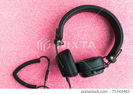 Black big headphones on pink glitter background. Black big headphones on pink glitter background. 75343465