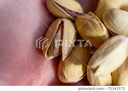Pistachio nuts a lot on childs hand macro image 75343573