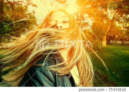 Young woman with wind swept hair backlit 75343616