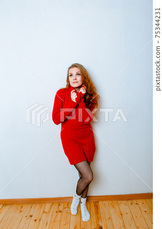 Portrait of ginger woman in red sweater in studio with isolated background.  75344231