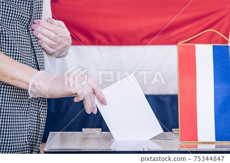 The woman is holding an envelope in her hand above the ballot paper. 75344847