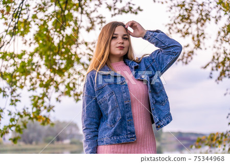 A young girl poses posing in a warm autumn evening. A young girl poses posing in a warm autumn evening. 75344968