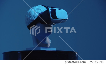 A greek head sculpture in VR glasses on the stand - blue lighting 75345196