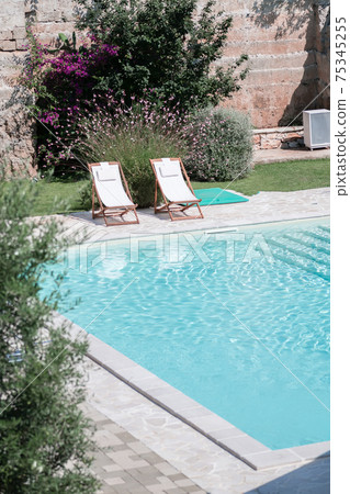 Swim pool with clear blue water and two sun bed on sunny day in a yard Swim pool with clear blue water and two sun bed on sunny day in a yard 75345255
