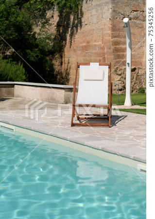 Swim pool with clear blue water and one sun bed on sunny day in a yard Swim pool with clear blue water and one sun bed on sunny day in a yard 75345256
