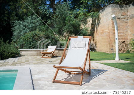 Swim pool with clear blue water and two sun bed on sunny day in a yard Swim pool with clear blue water and two sun bed on sunny day in a yard 75345257