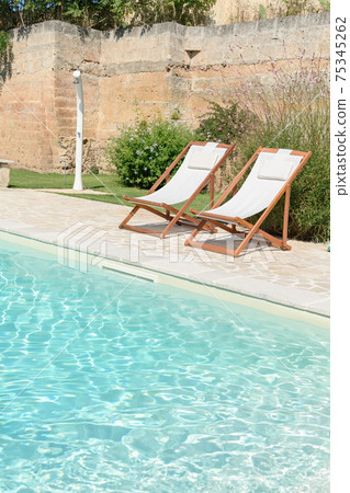 Swim pool with clear blue water and two sun bed on sunny day in a yard Swim pool with clear blue water and two sun bed on sunny day in a yard 75345262